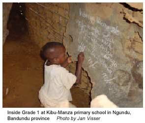 Small child writing on a blackboard at Kibu-Manza primary school. Photo by Jan Visser